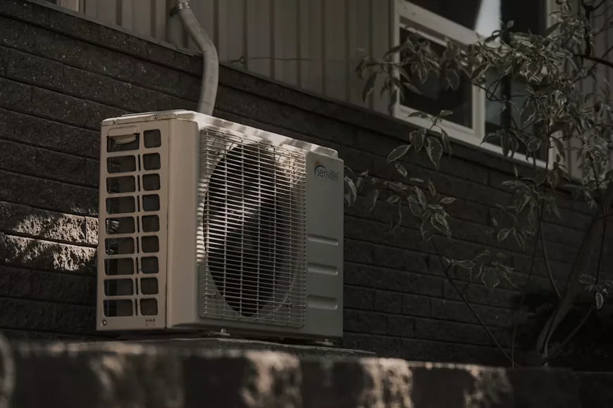 Technician inspecting an outdoor air conditioning unit to identify the source of an unusual noise